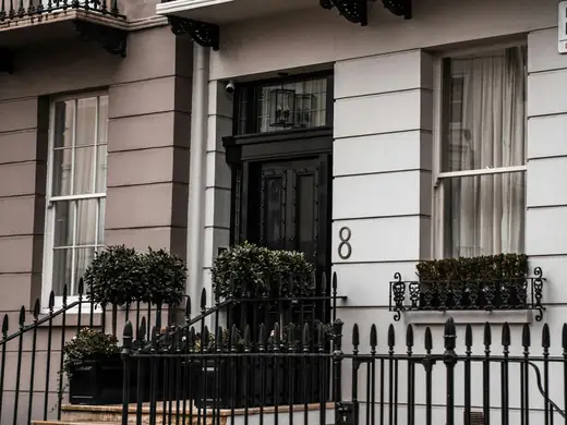 The front of a white London townhouse with black railings